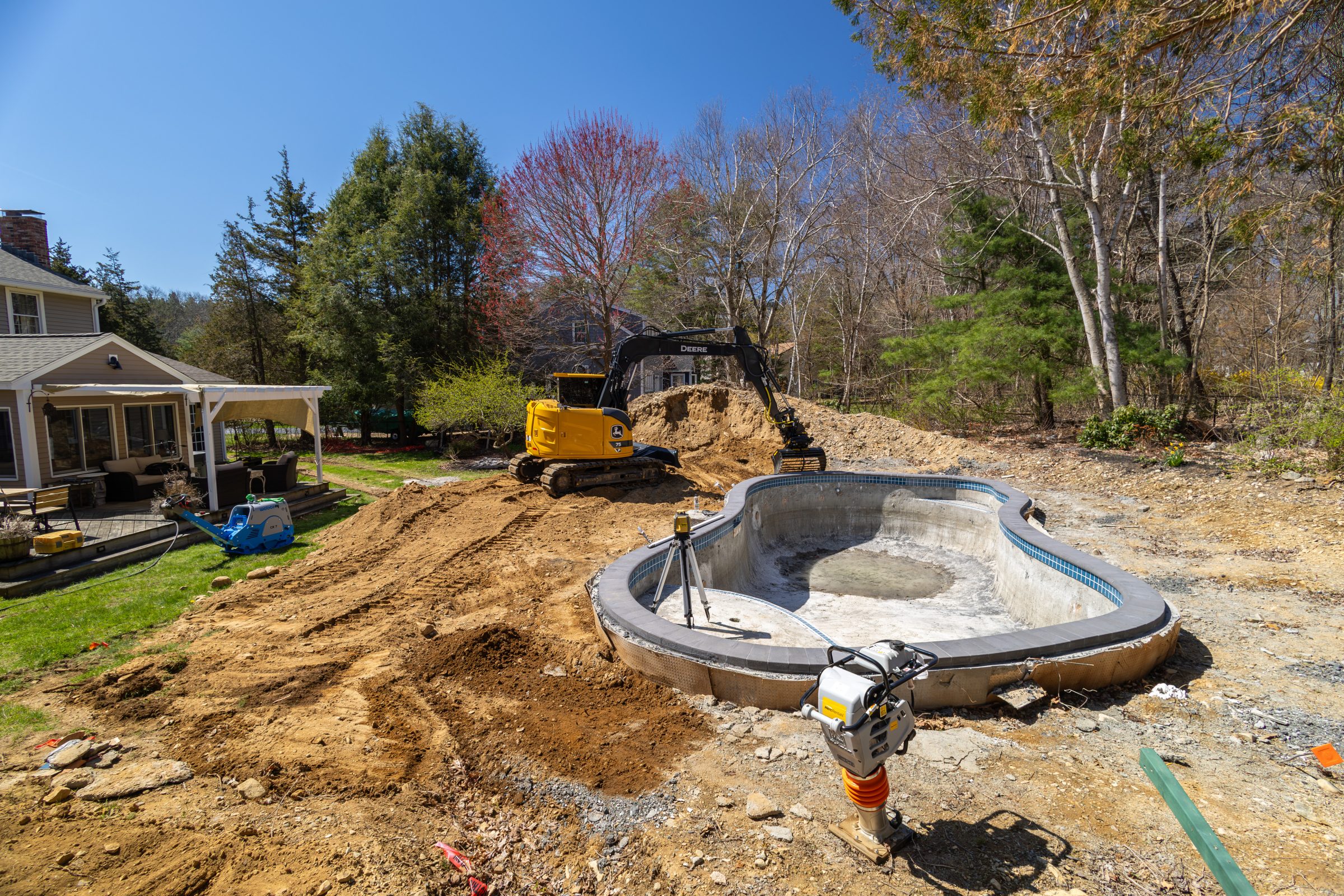 Backyard pool construction with excavator and dirt piles