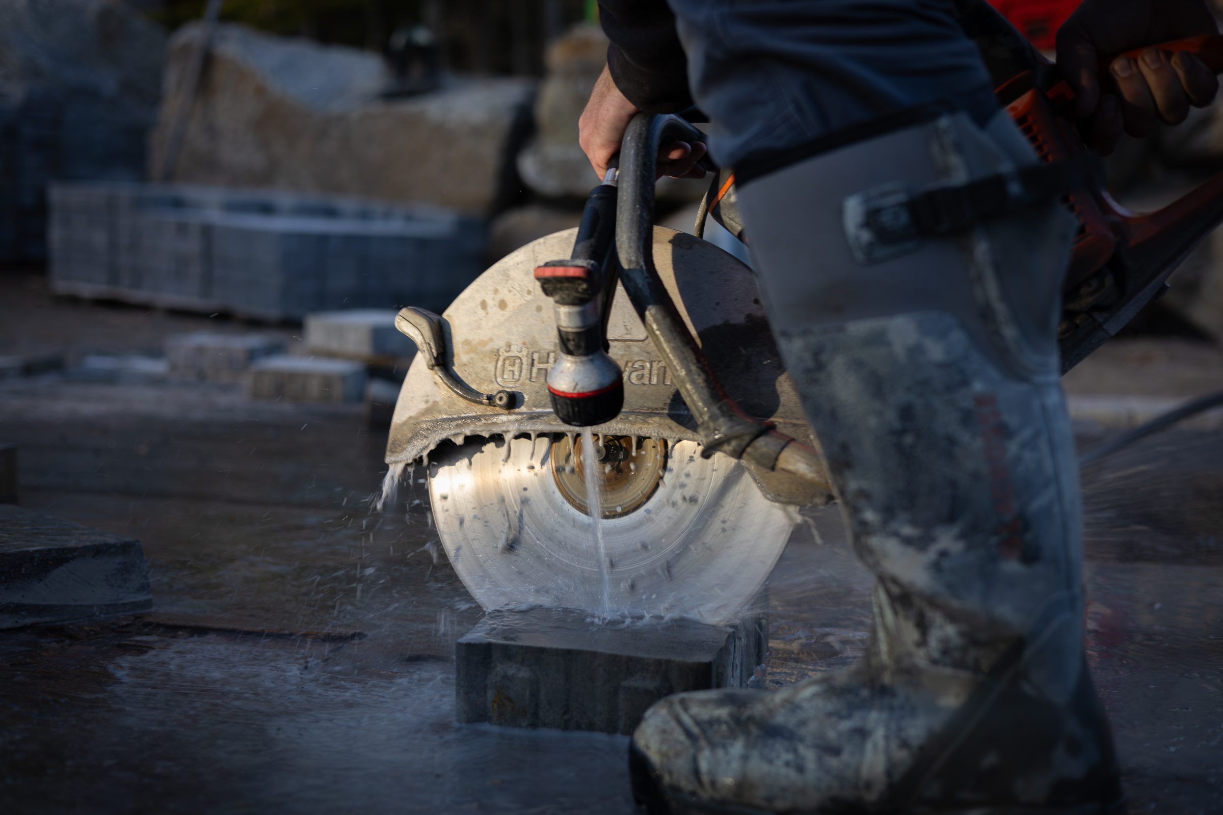 Worker cutting concrete block with wet circular saw
