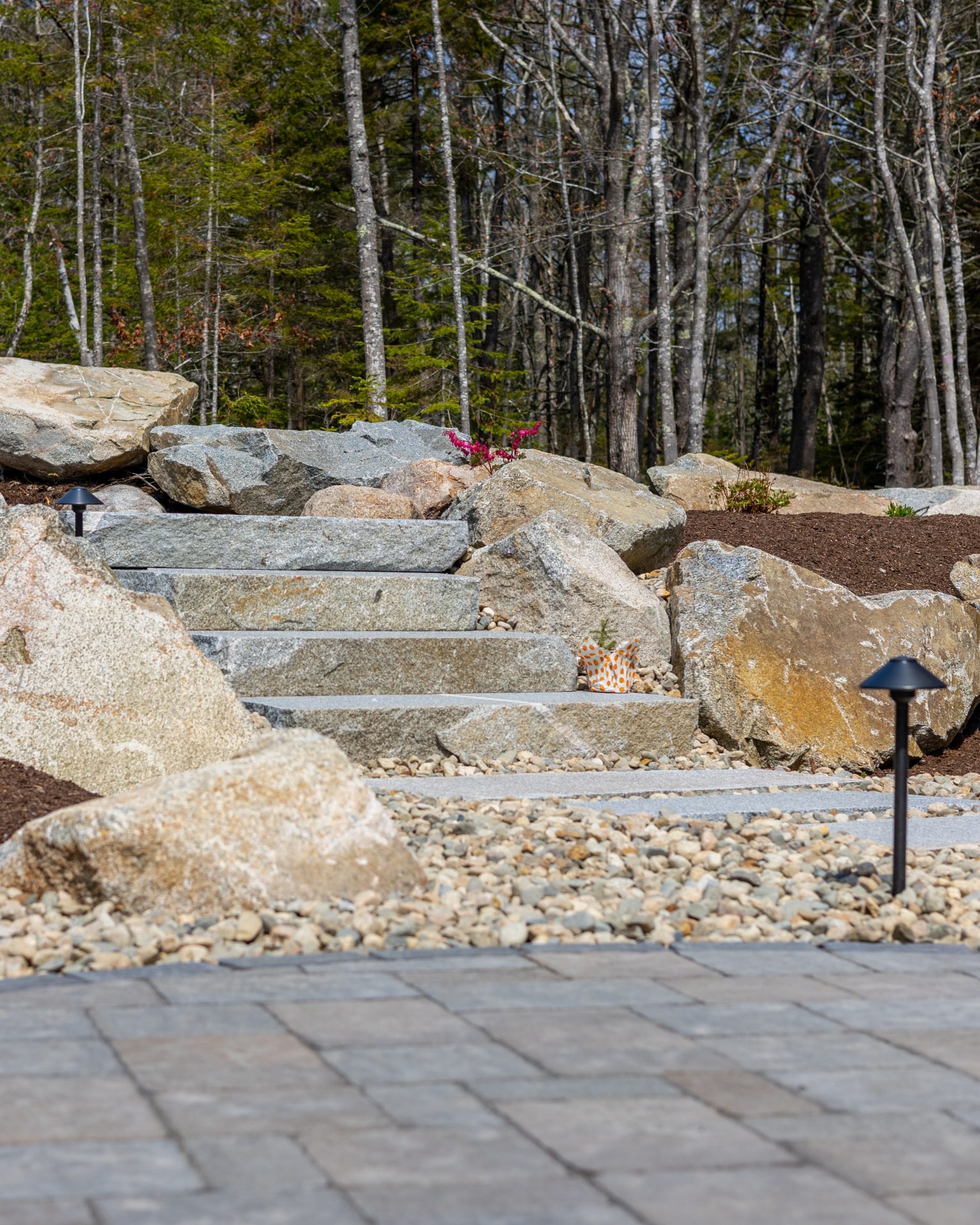 Stone garden steps with boulders and forest backdrop