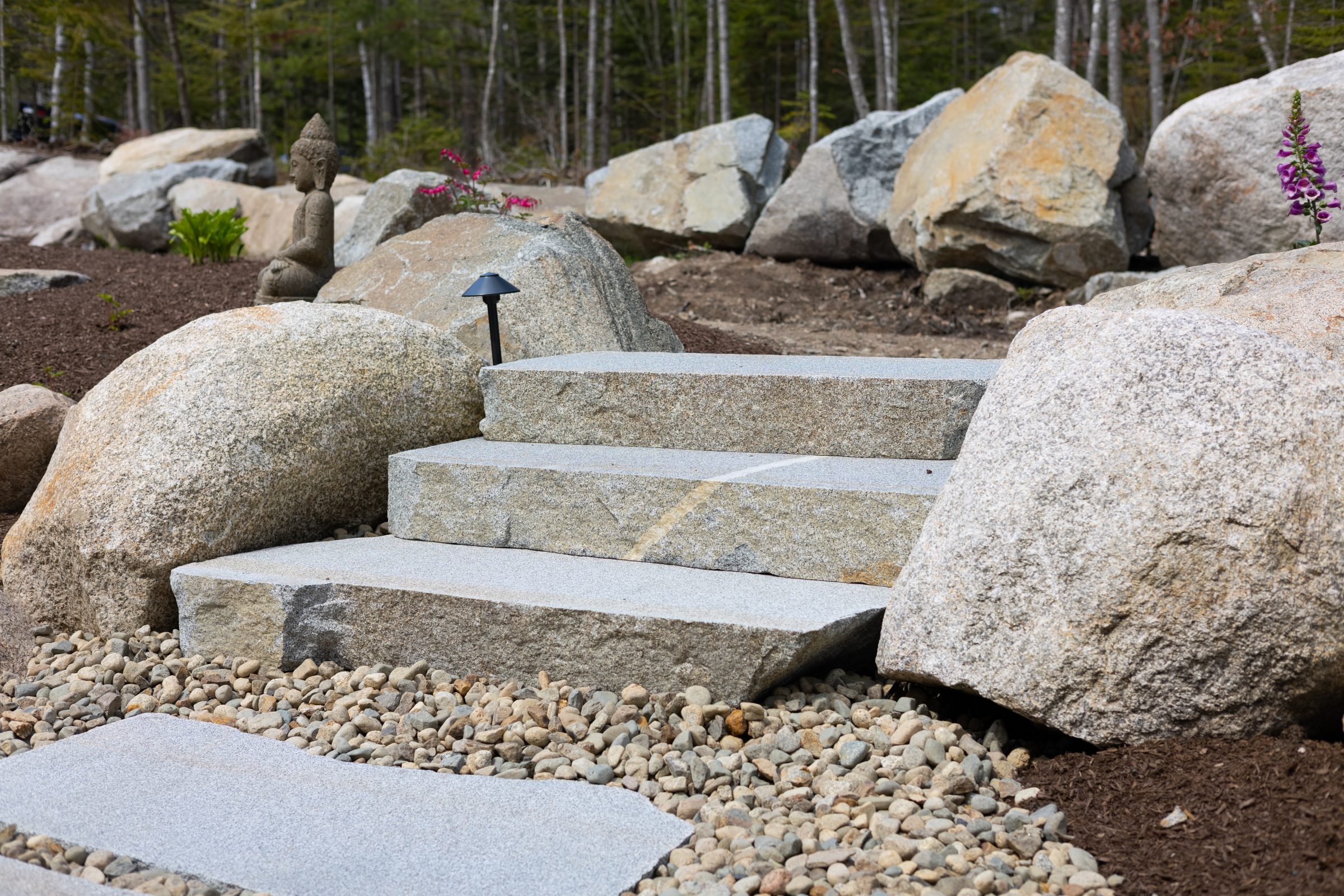 Stone garden steps with Buddha statue and boulders