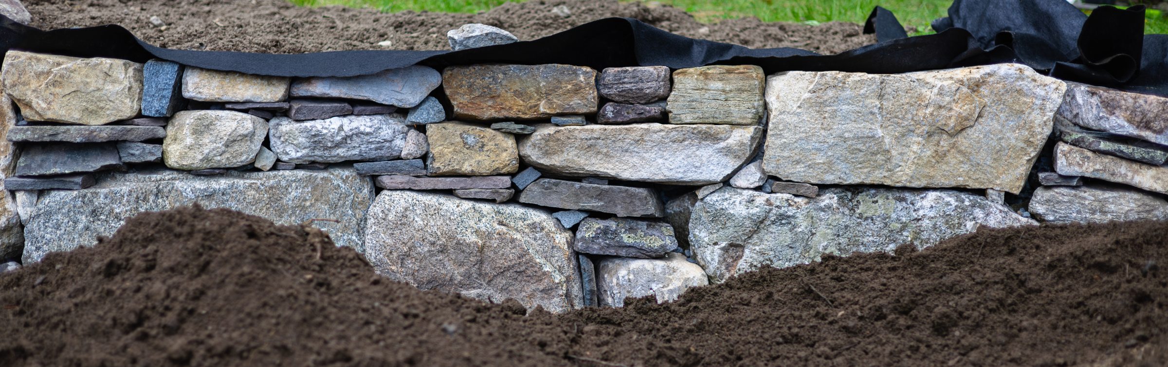 Stacked stone retaining wall with soil foreground