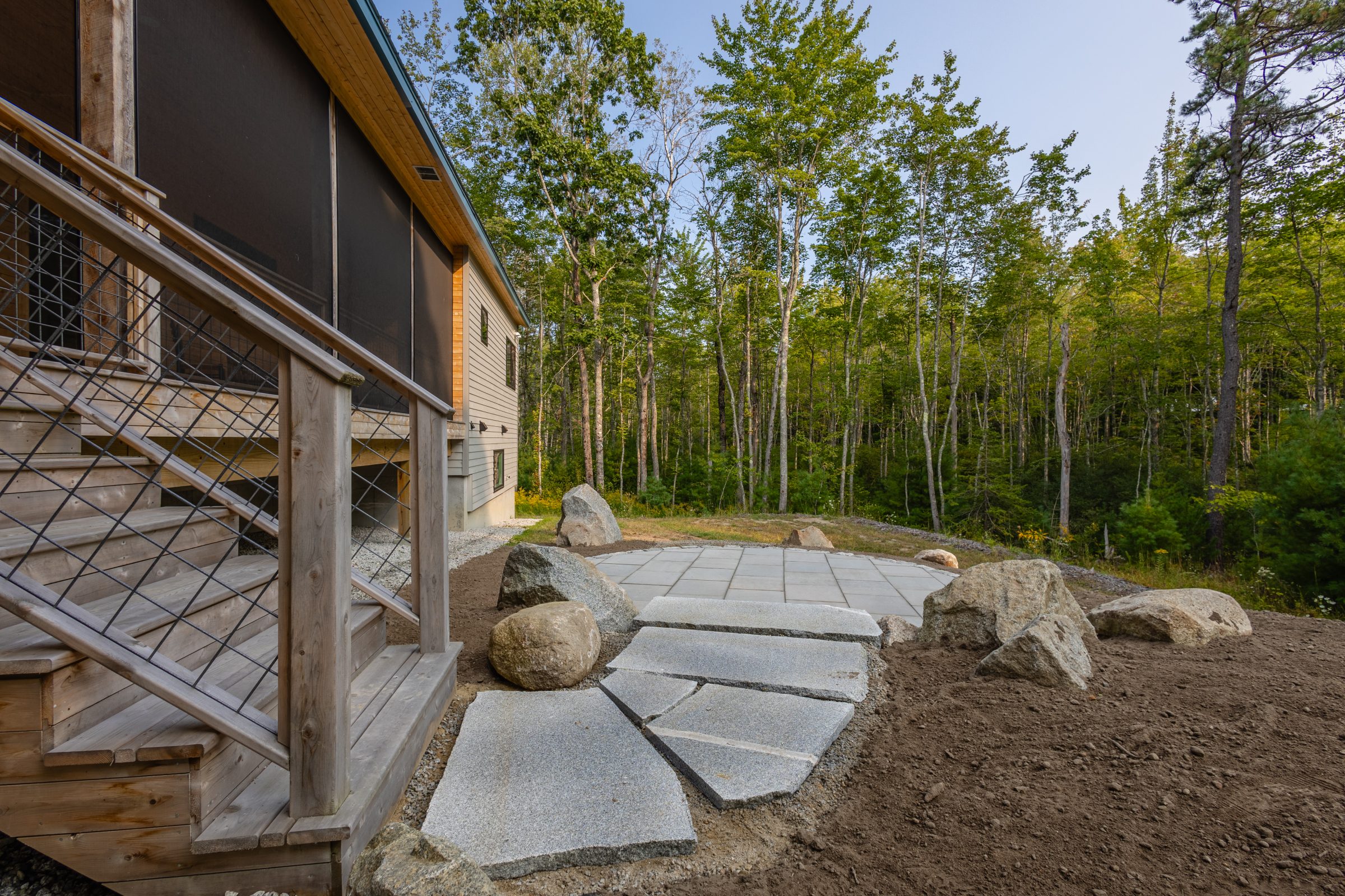 Wooded backyard patio with stone path and deck