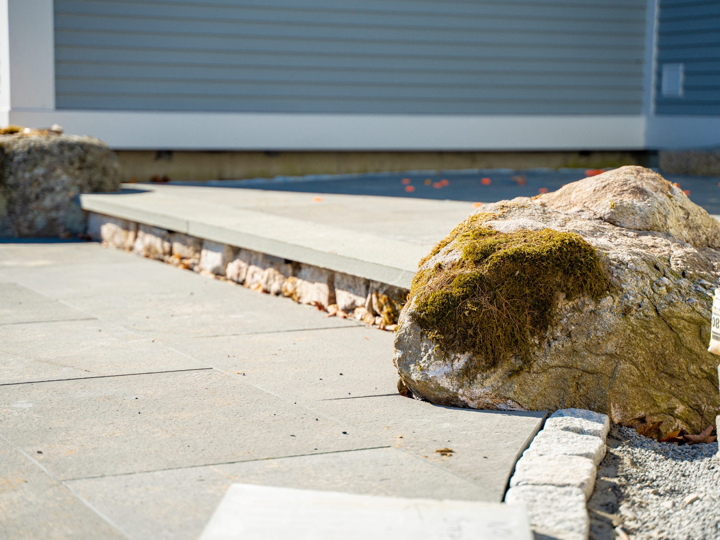 Moss-covered rock beside modern concrete walkway