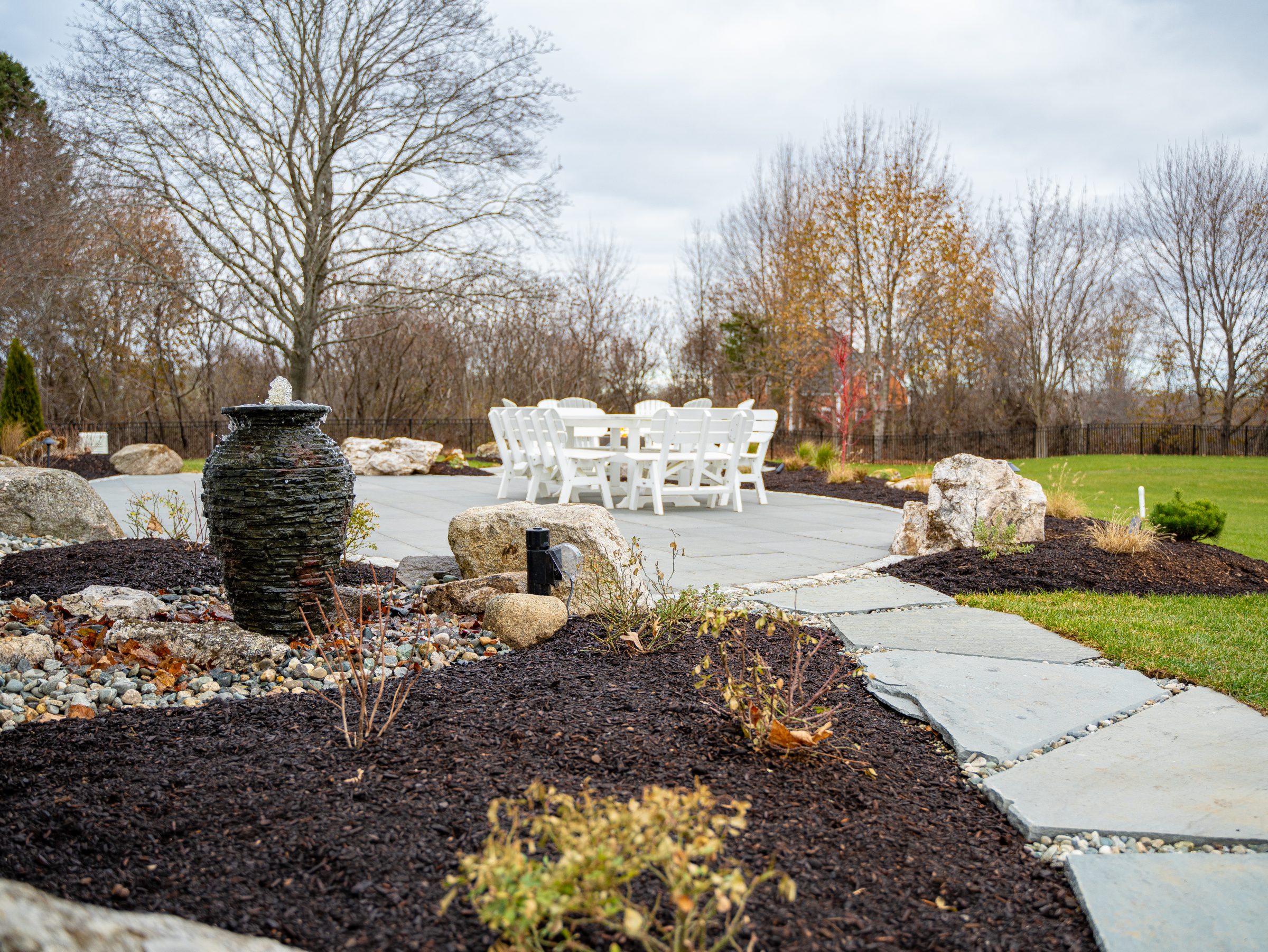 Landscaped backyard patio with fountain and dining set
