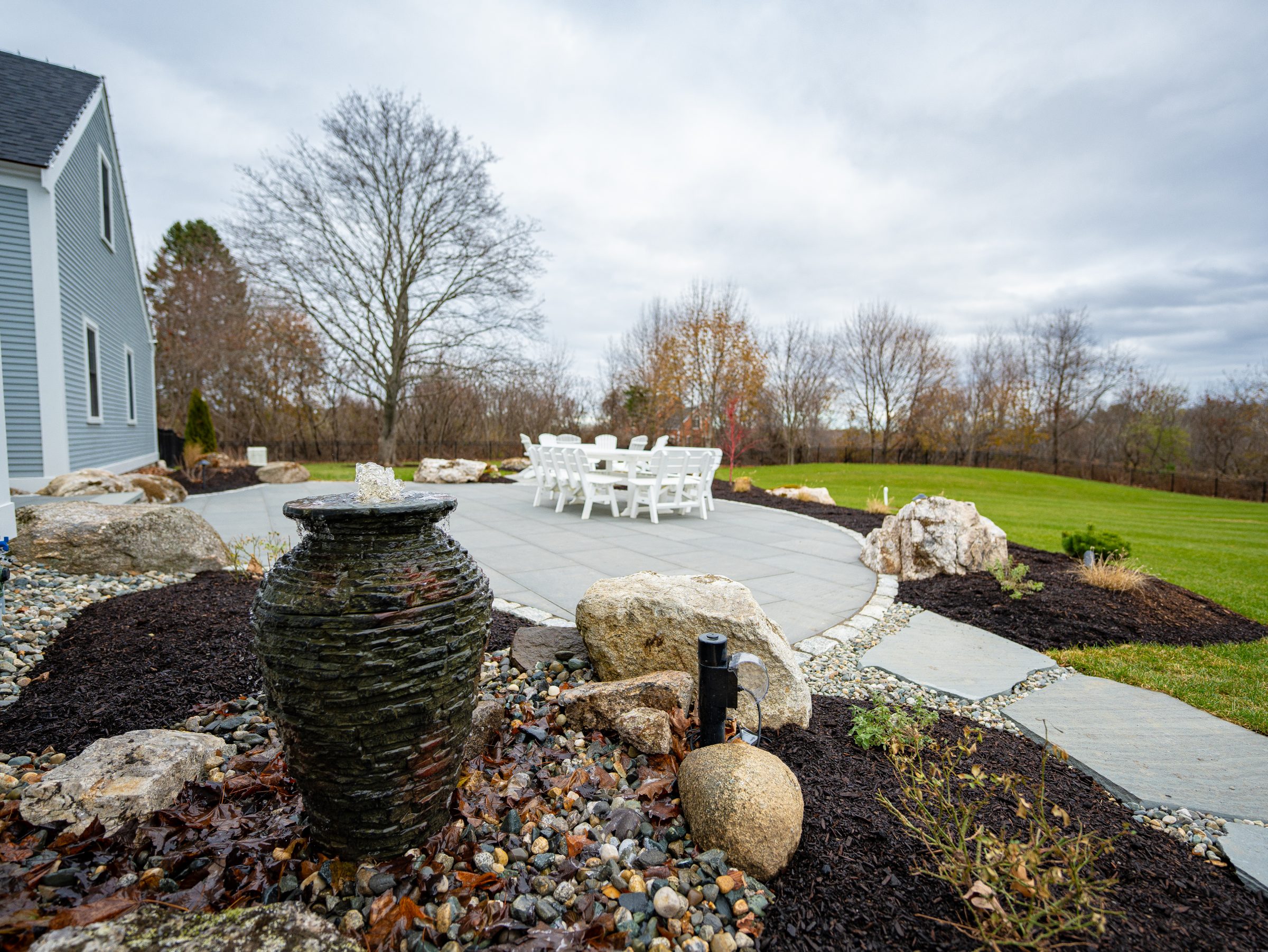 Landscaped backyard patio with fountain and dining set