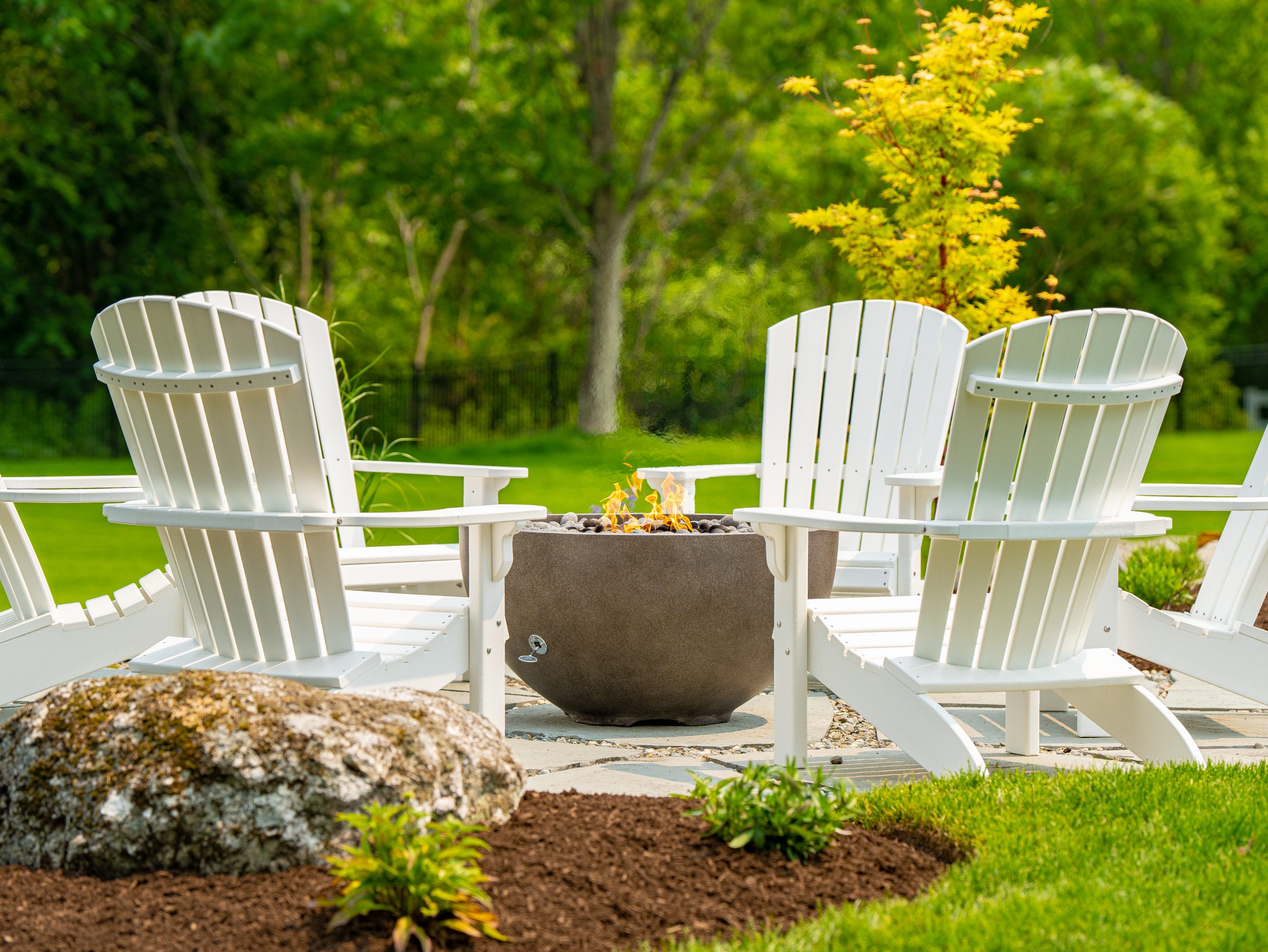 White Adirondack chairs around backyard fire pit