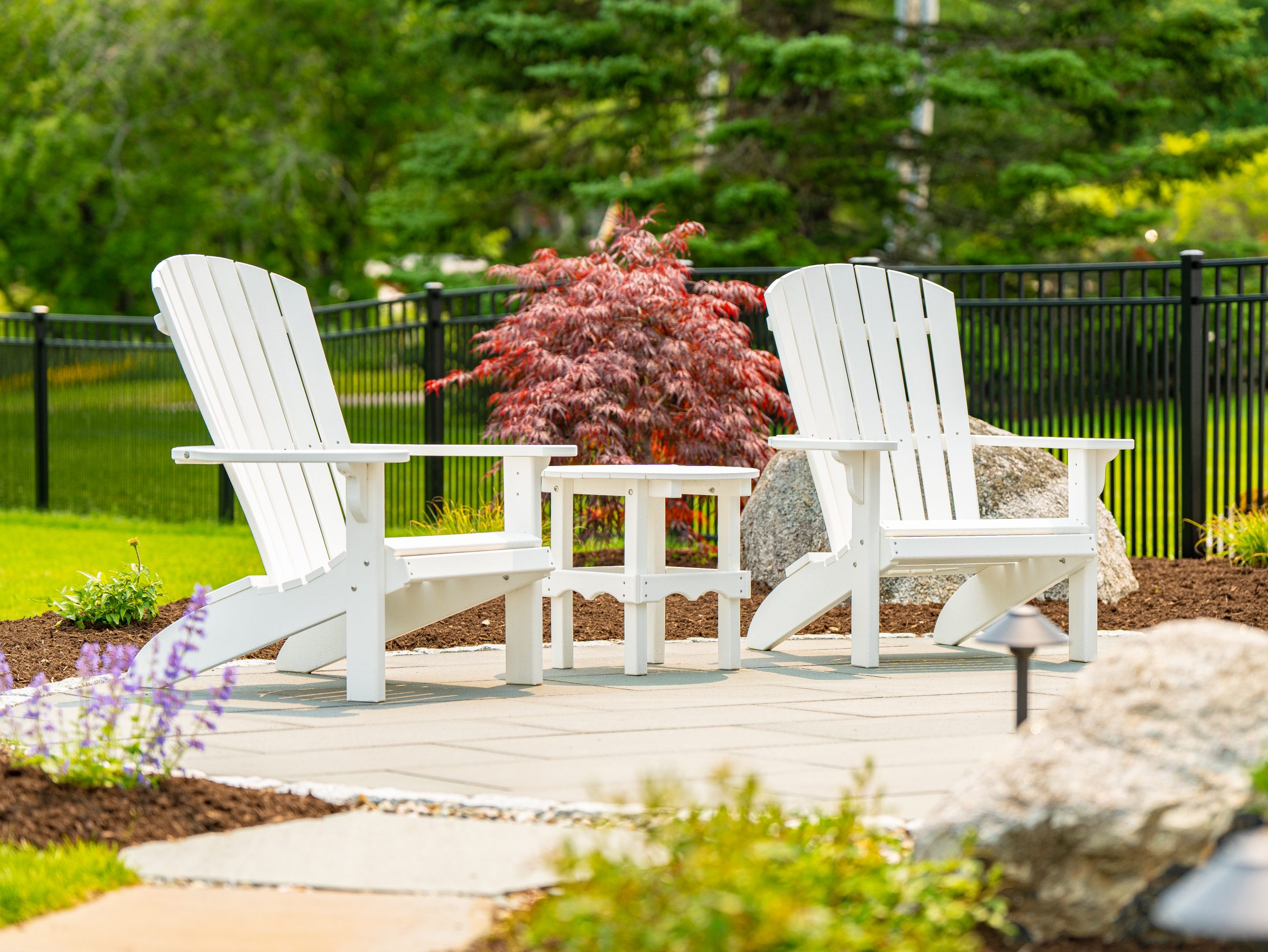 White Adirondack chairs on landscaped backyard patio