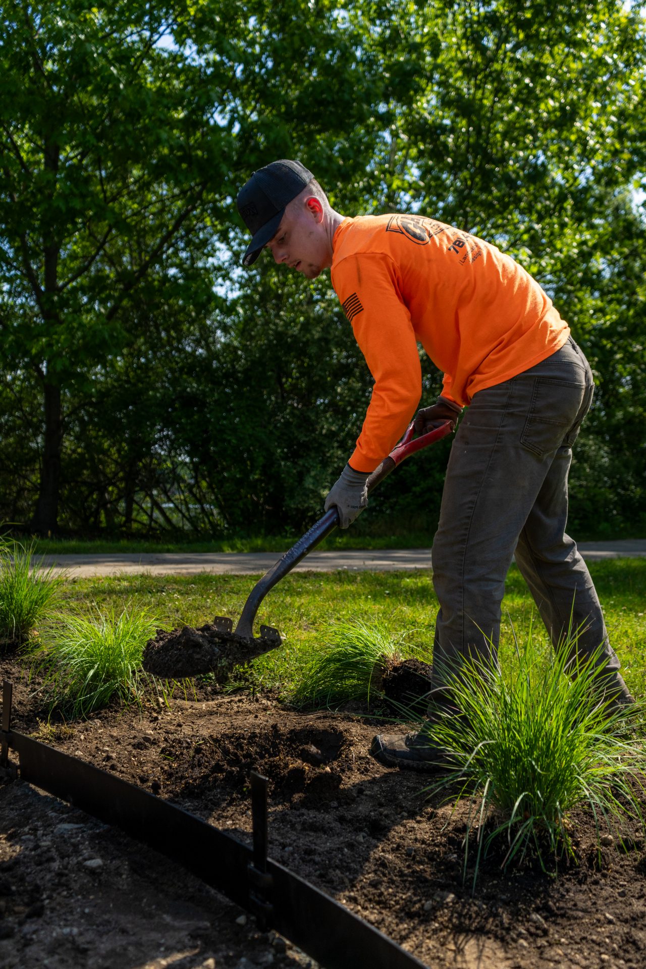 Man digging soil in landscaped garden bed