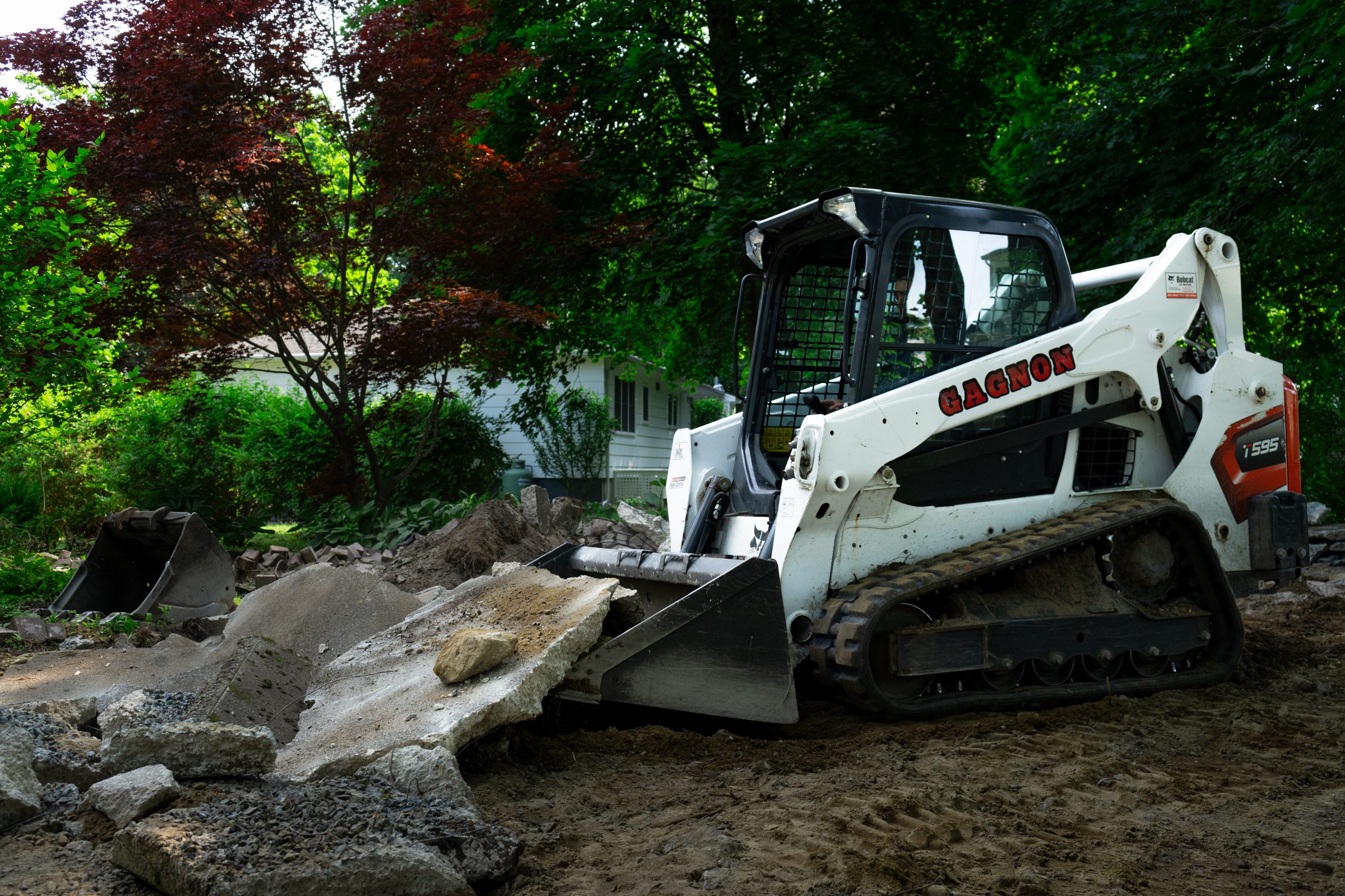 Skid-steer loader moving broken concrete in yard