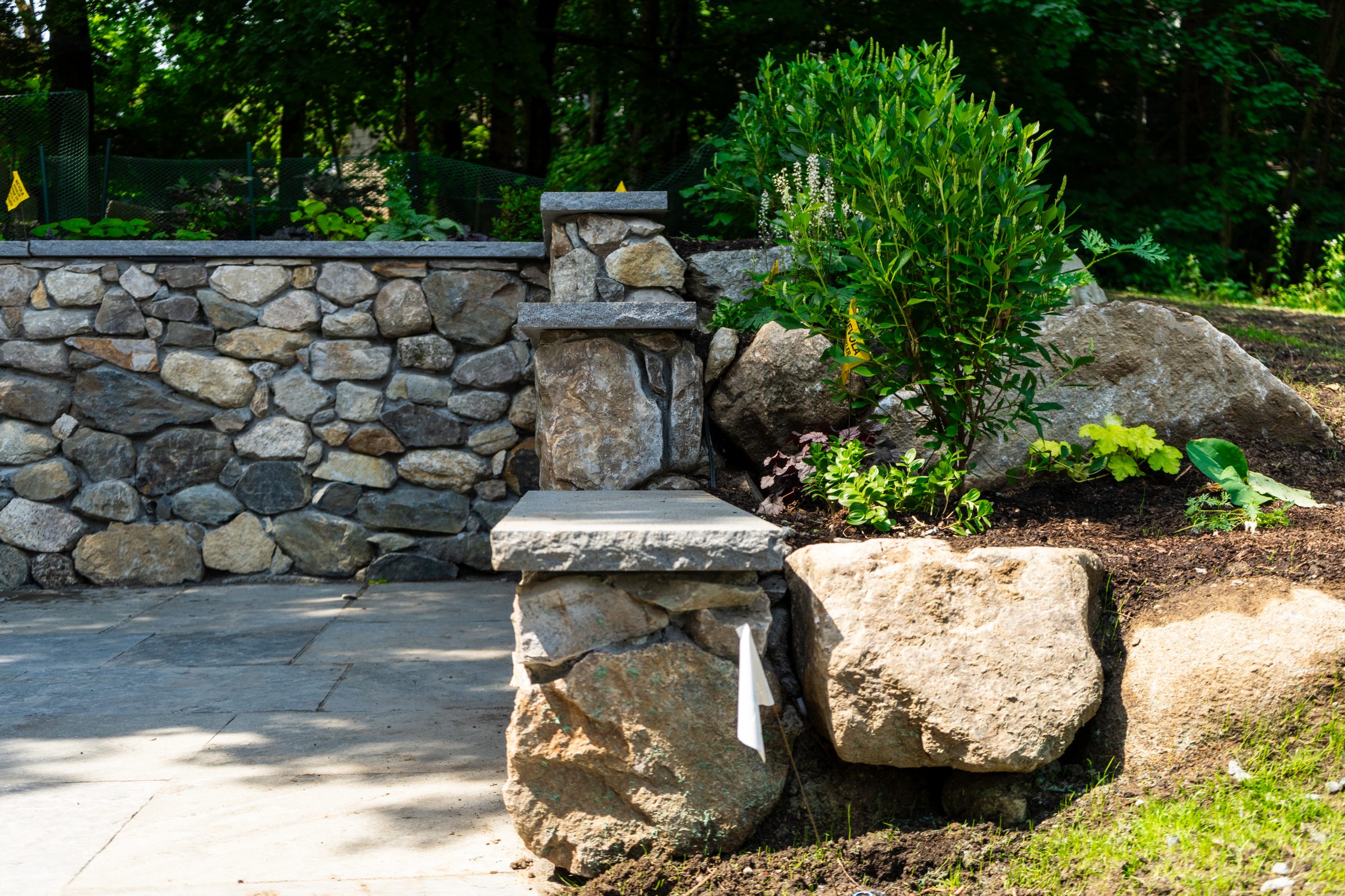 Stone retaining wall with landscaped garden and patio