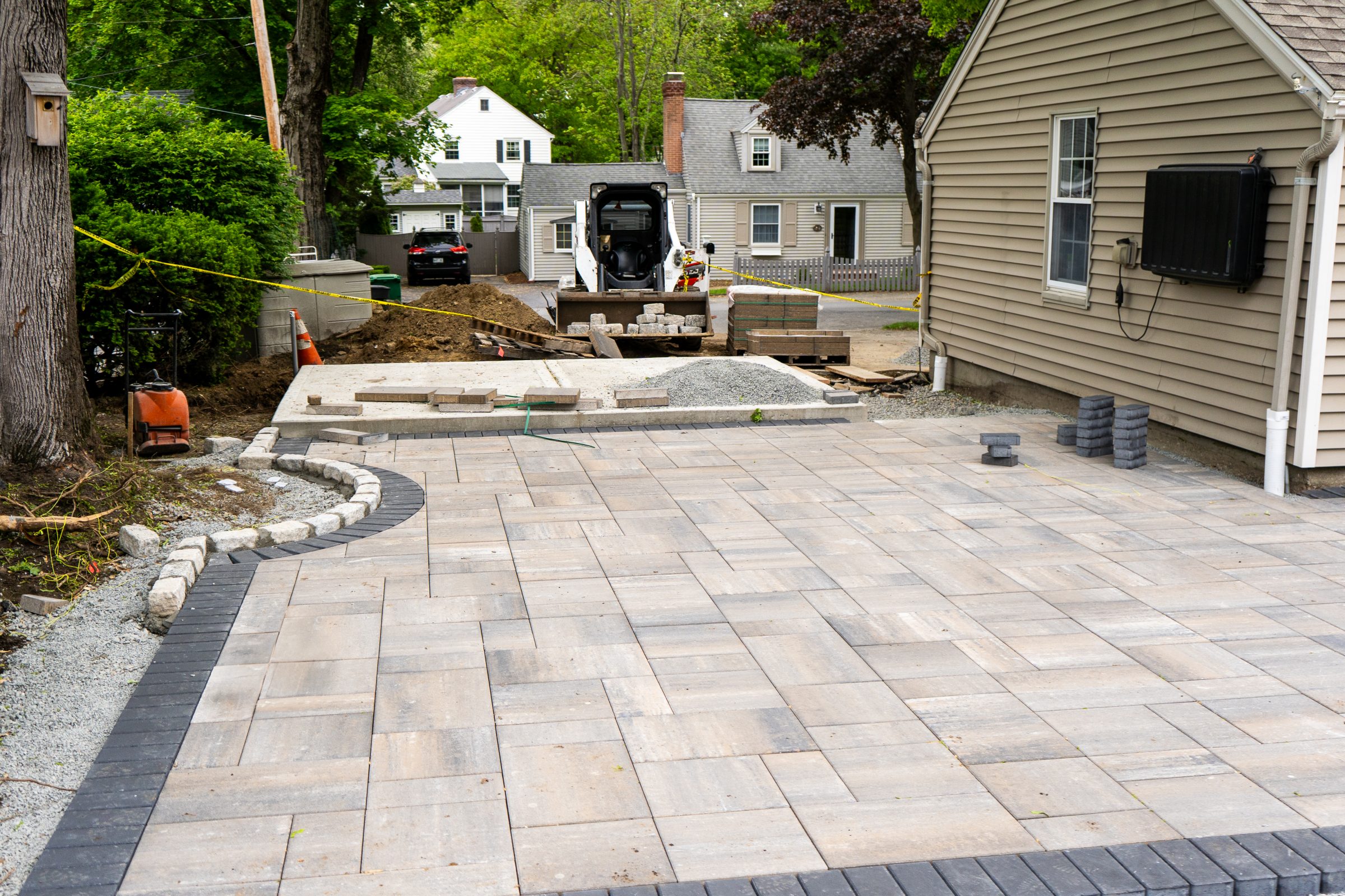 Driveway patio under construction with pavers and skid-steer