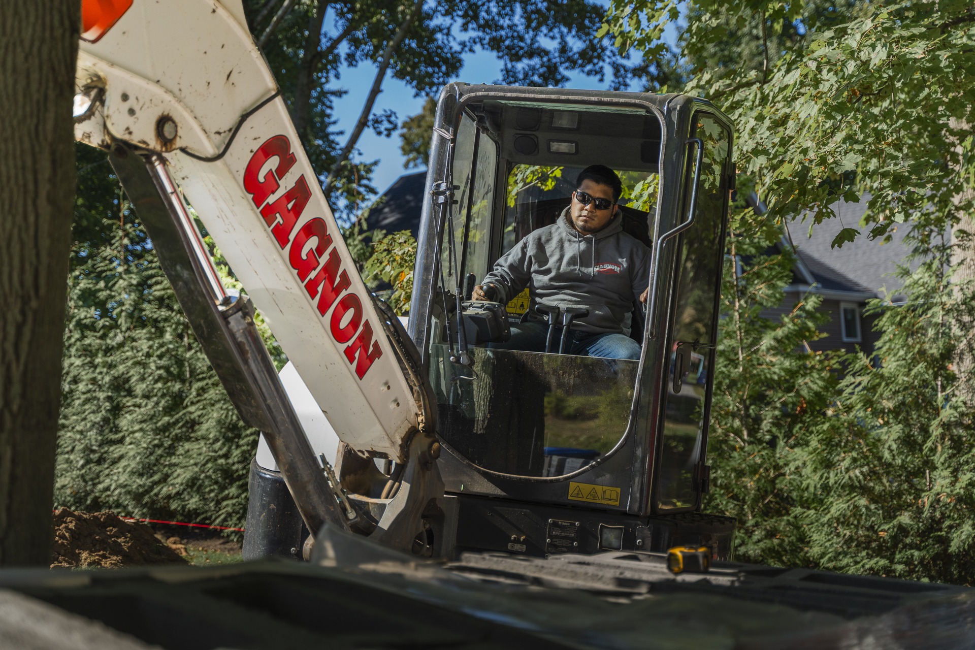 Man operating mini excavator in residential yard