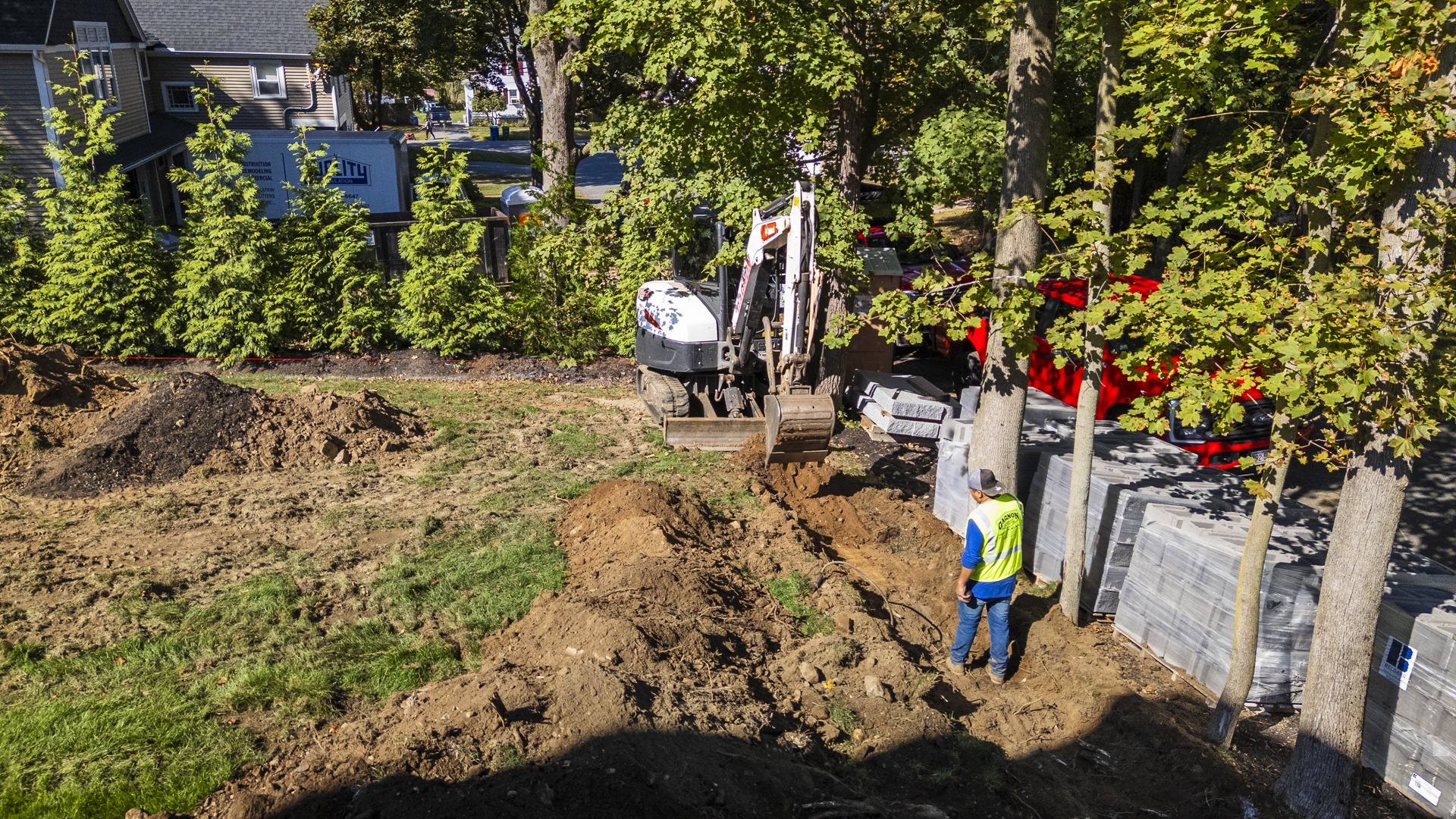 Excavator digging trench in residential backyard