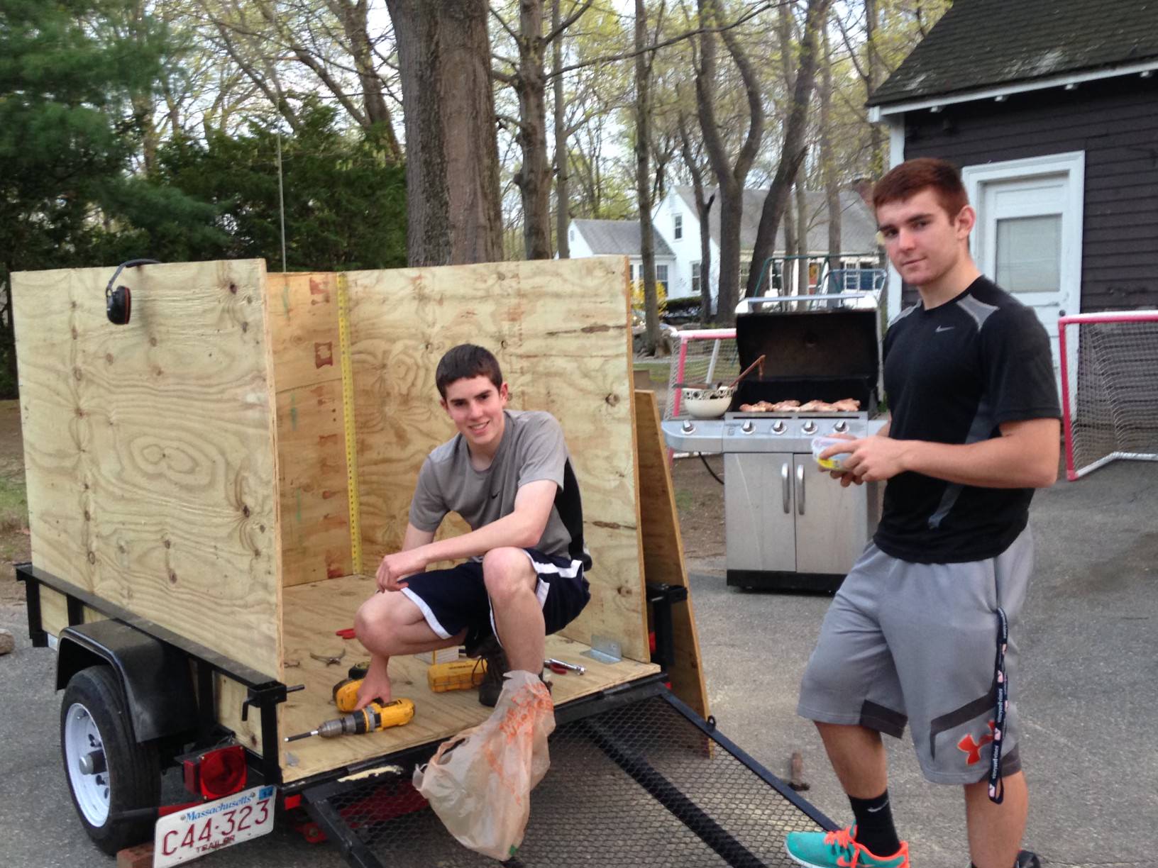 Two young men building trailer and grilling outdoors