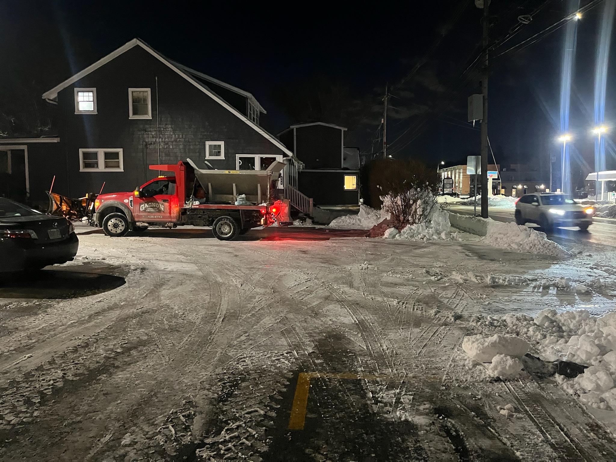 Snowplow truck clearing snowy parking lot at night