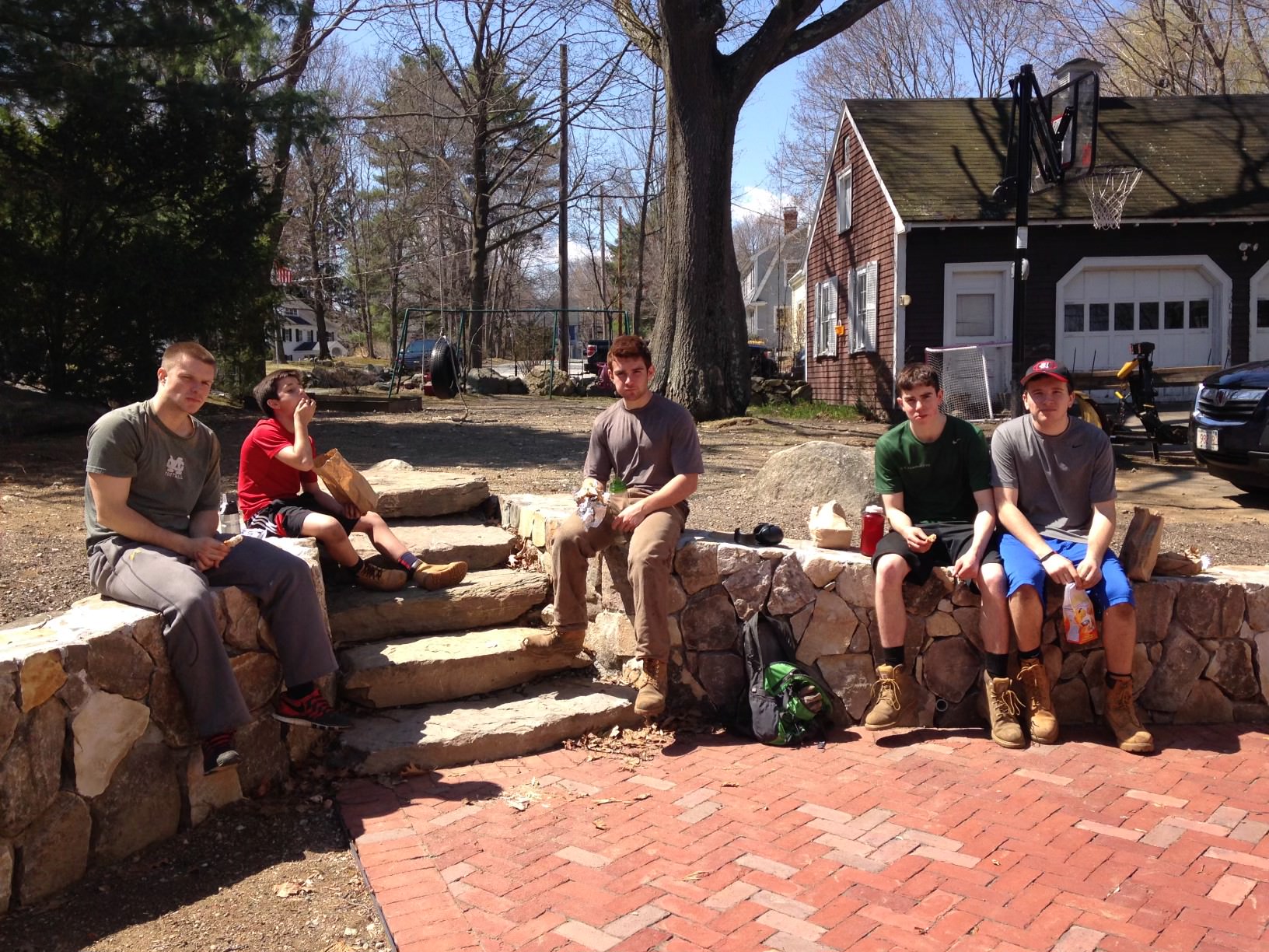 Five young men sitting outdoors eating snacks