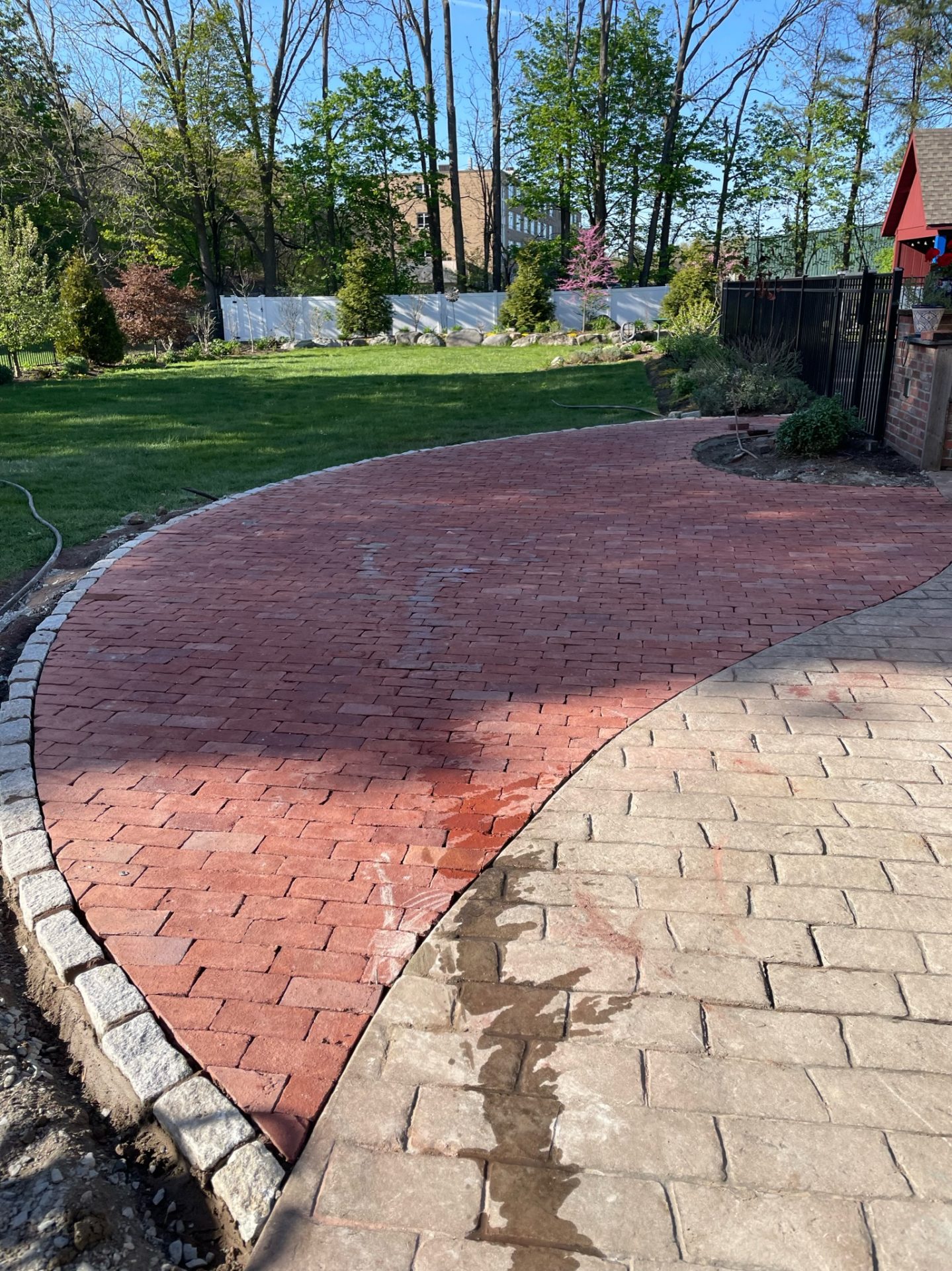 Curved red brick patio in landscaped backyard