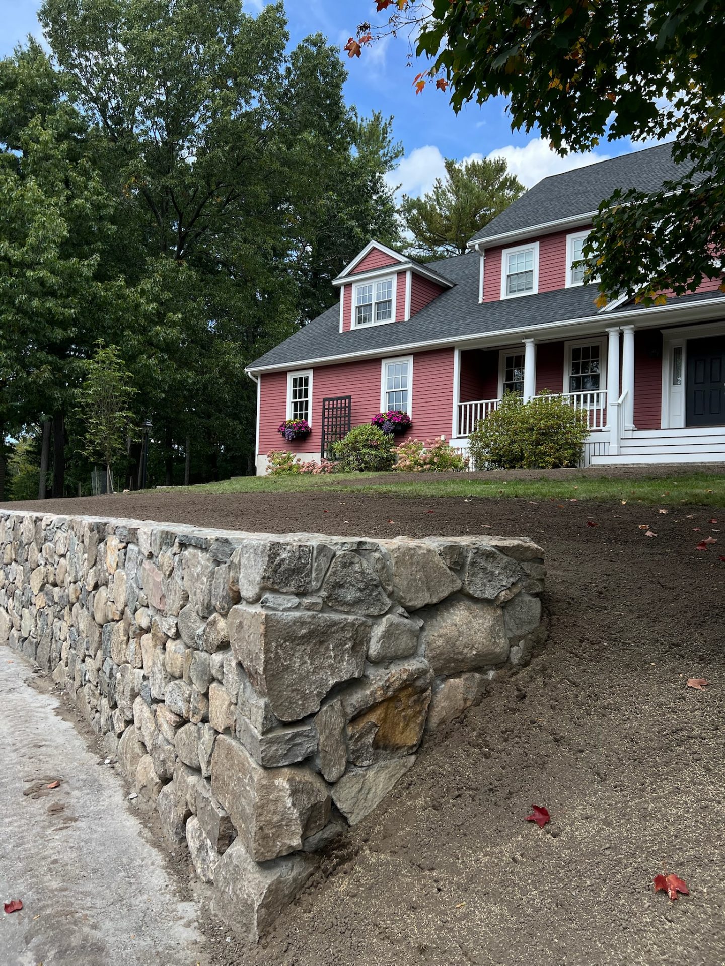 Red house with white trim and stone wall