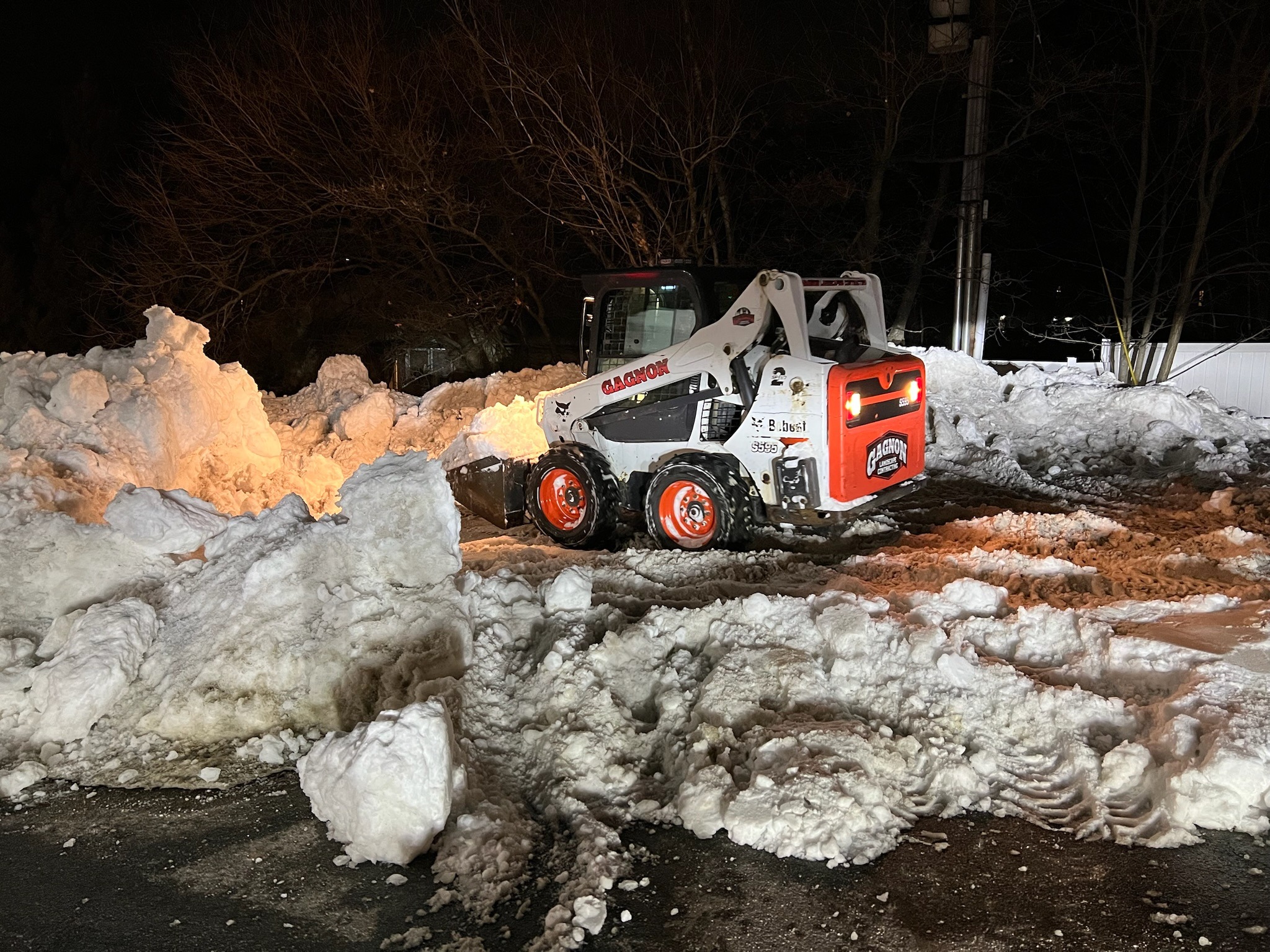 Skid-steer loader clearing snow at night