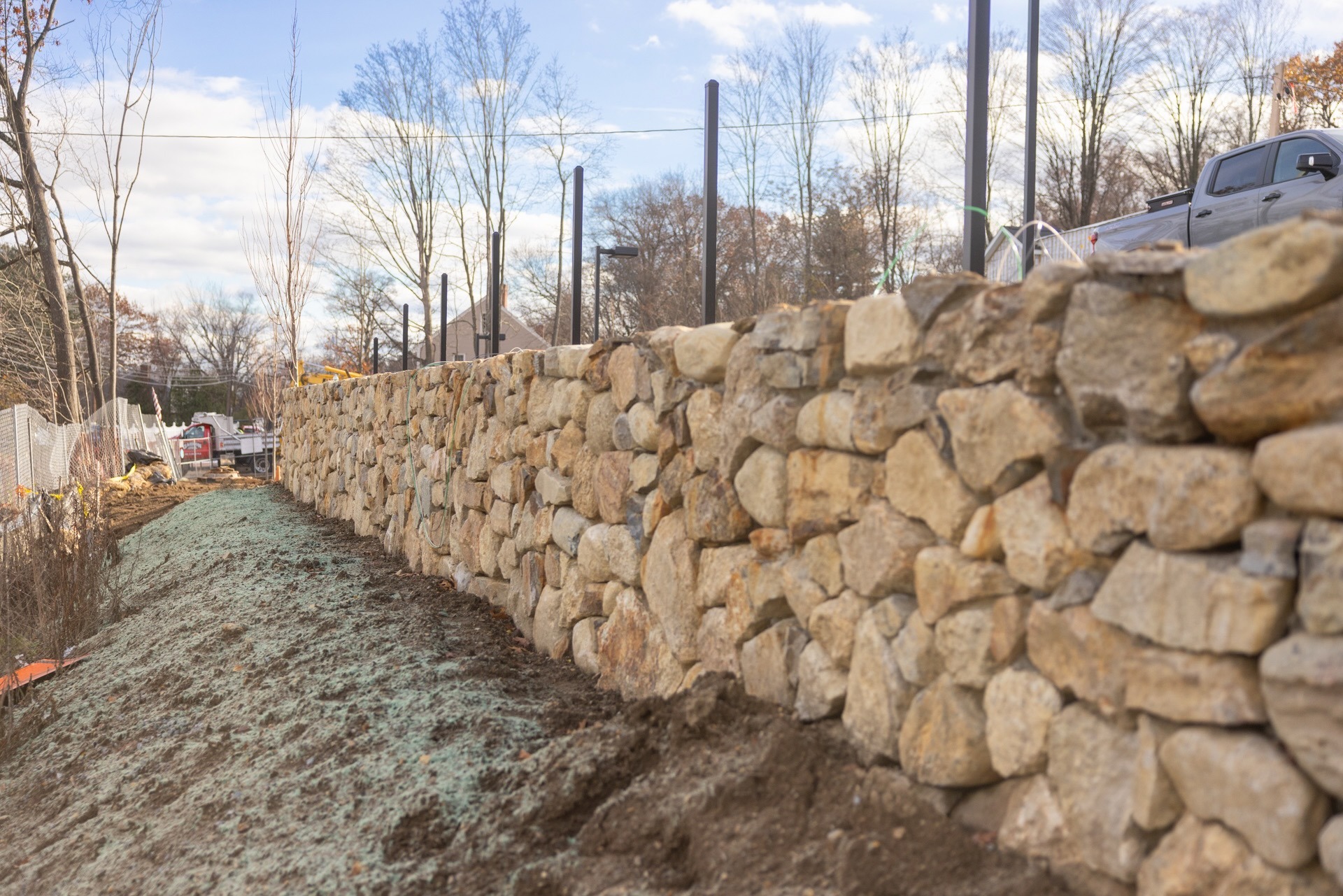 Stone retaining wall under construction along dirt path