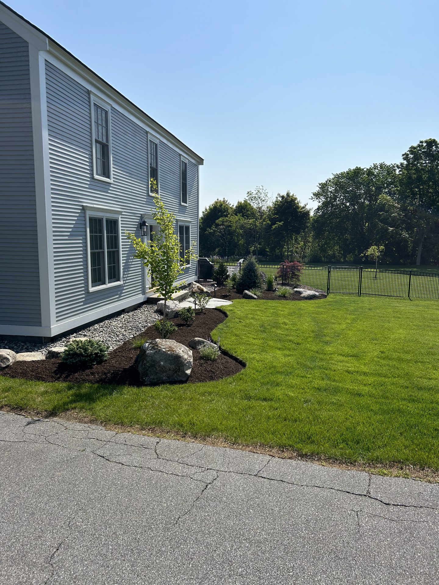 Landscaped backyard beside gray two-story house
