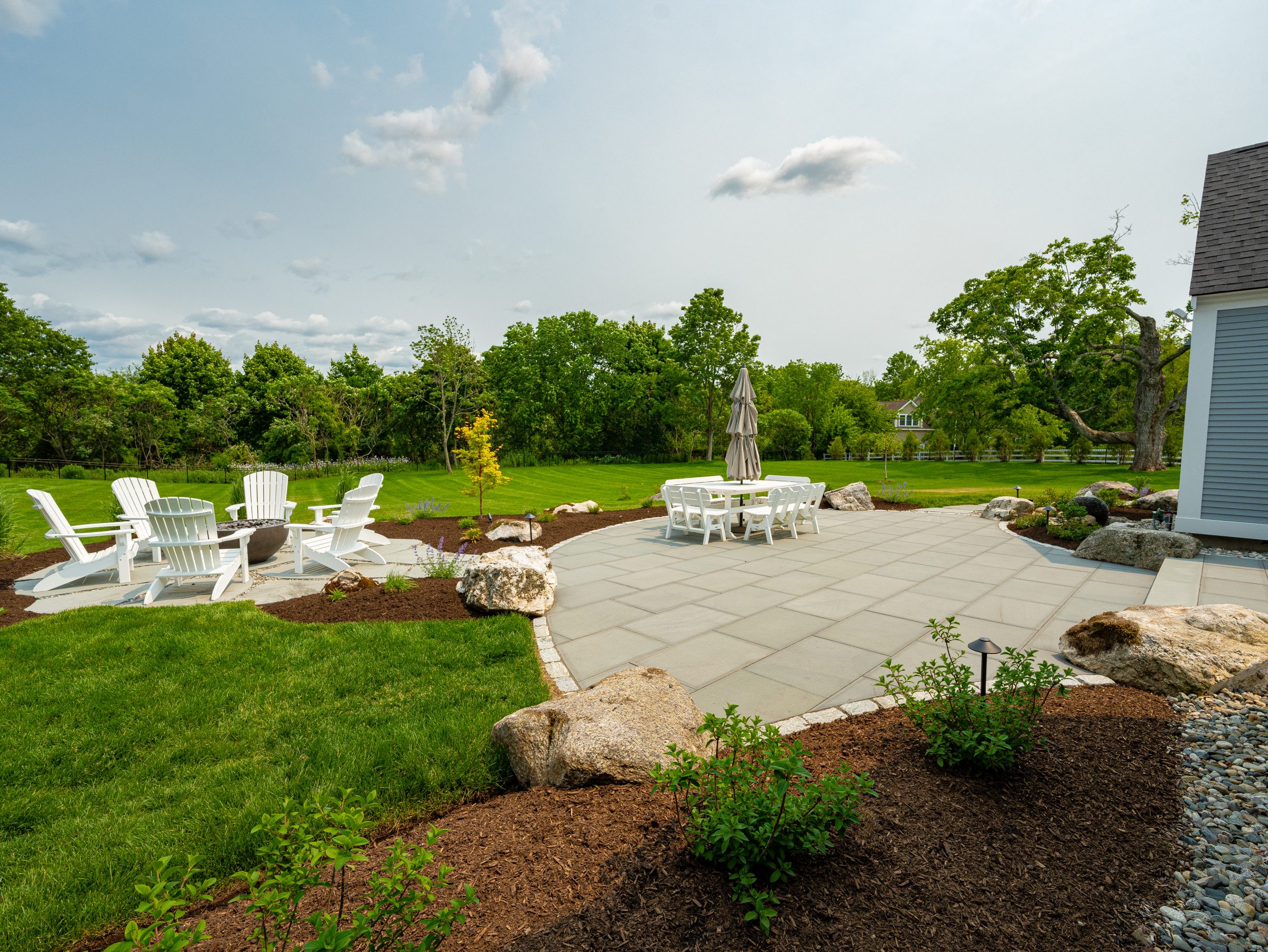 Landscaped backyard patio with fire pit and dining set