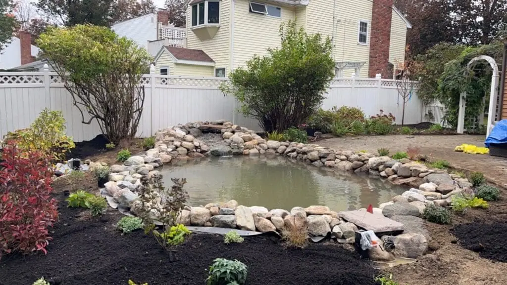 Back yard pond with stone around the pond with landscape design