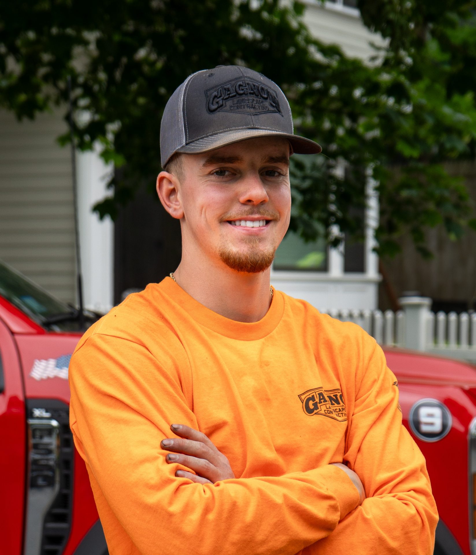 Smiling worker in orange shirt and gray cap