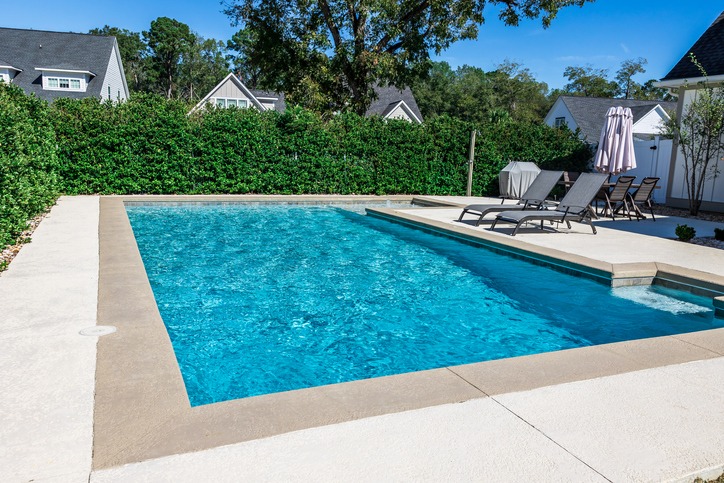 Backyard swimming pool with lounge chairs and umbrellas