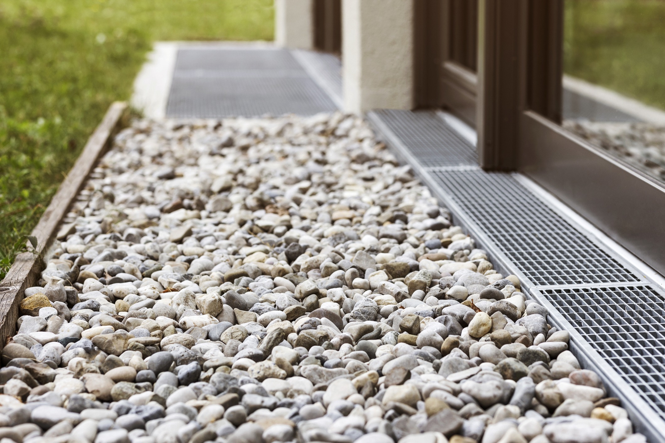 Gravel border with drainage grate beside house