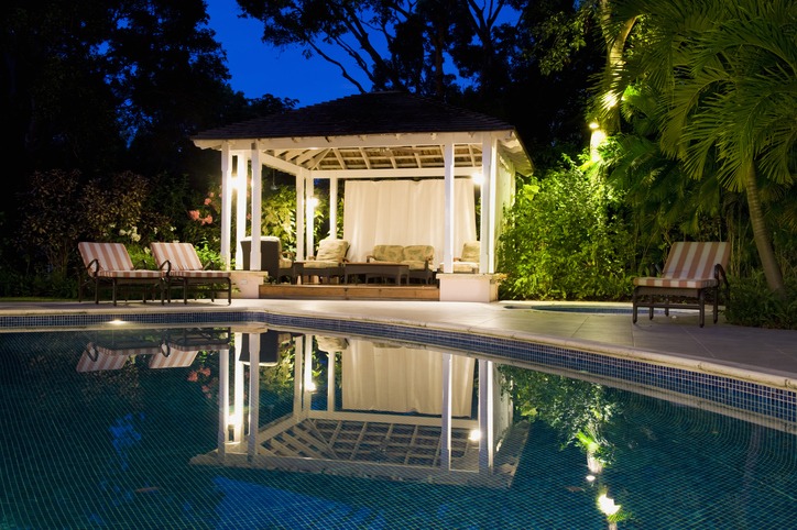 Illuminated gazebo reflected in swimming pool at night