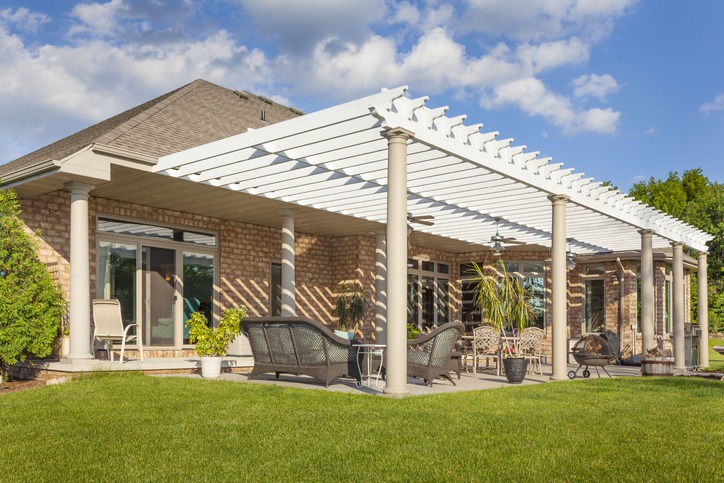 Backyard patio with white pergola and seating