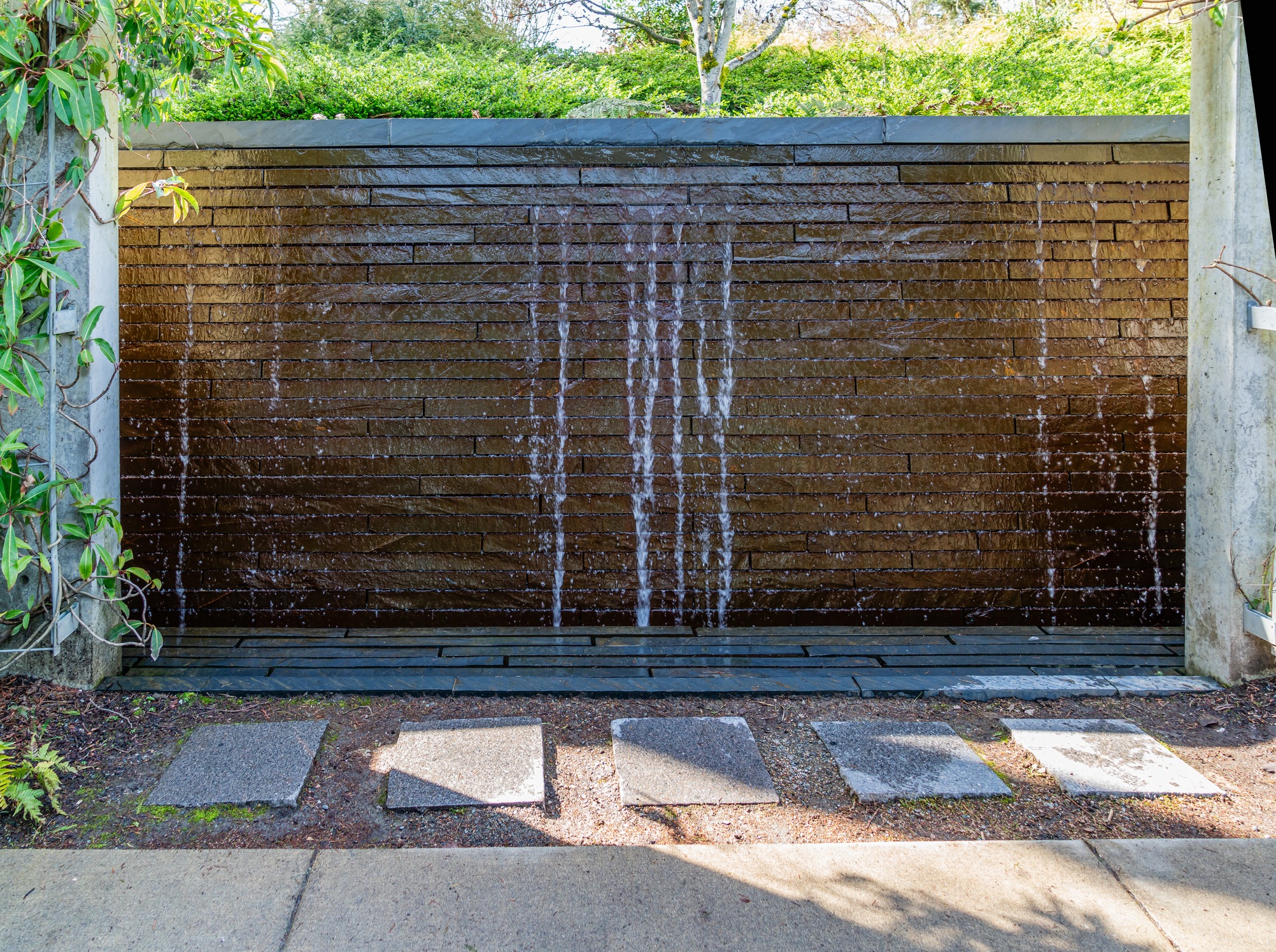 Modern stone wall waterfall in landscaped garden