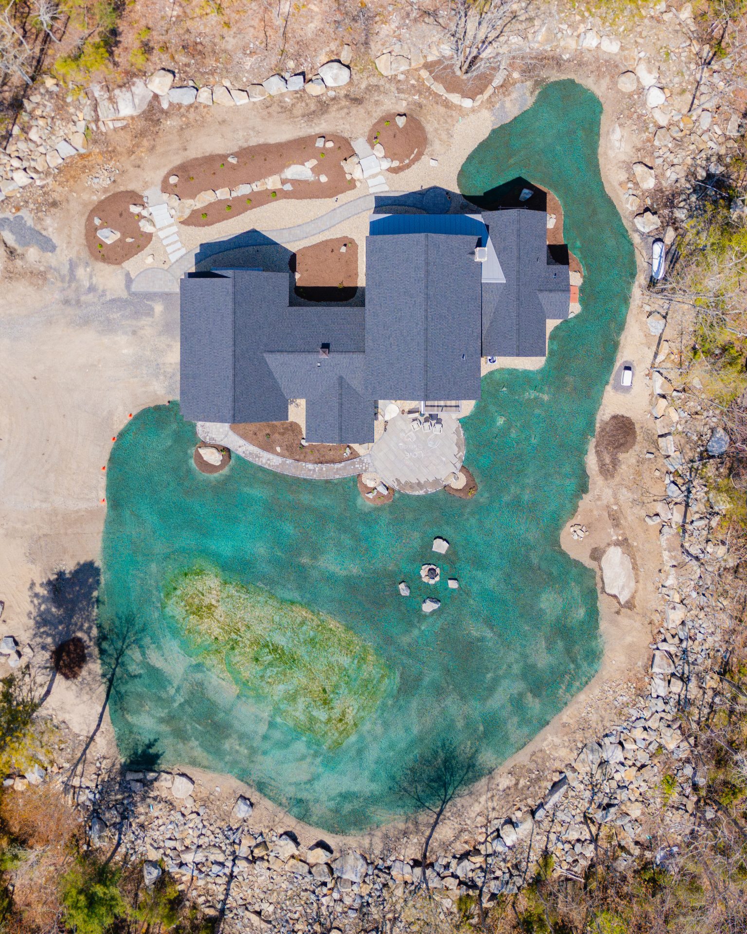 Aerial view of house surrounded by turquoise pond