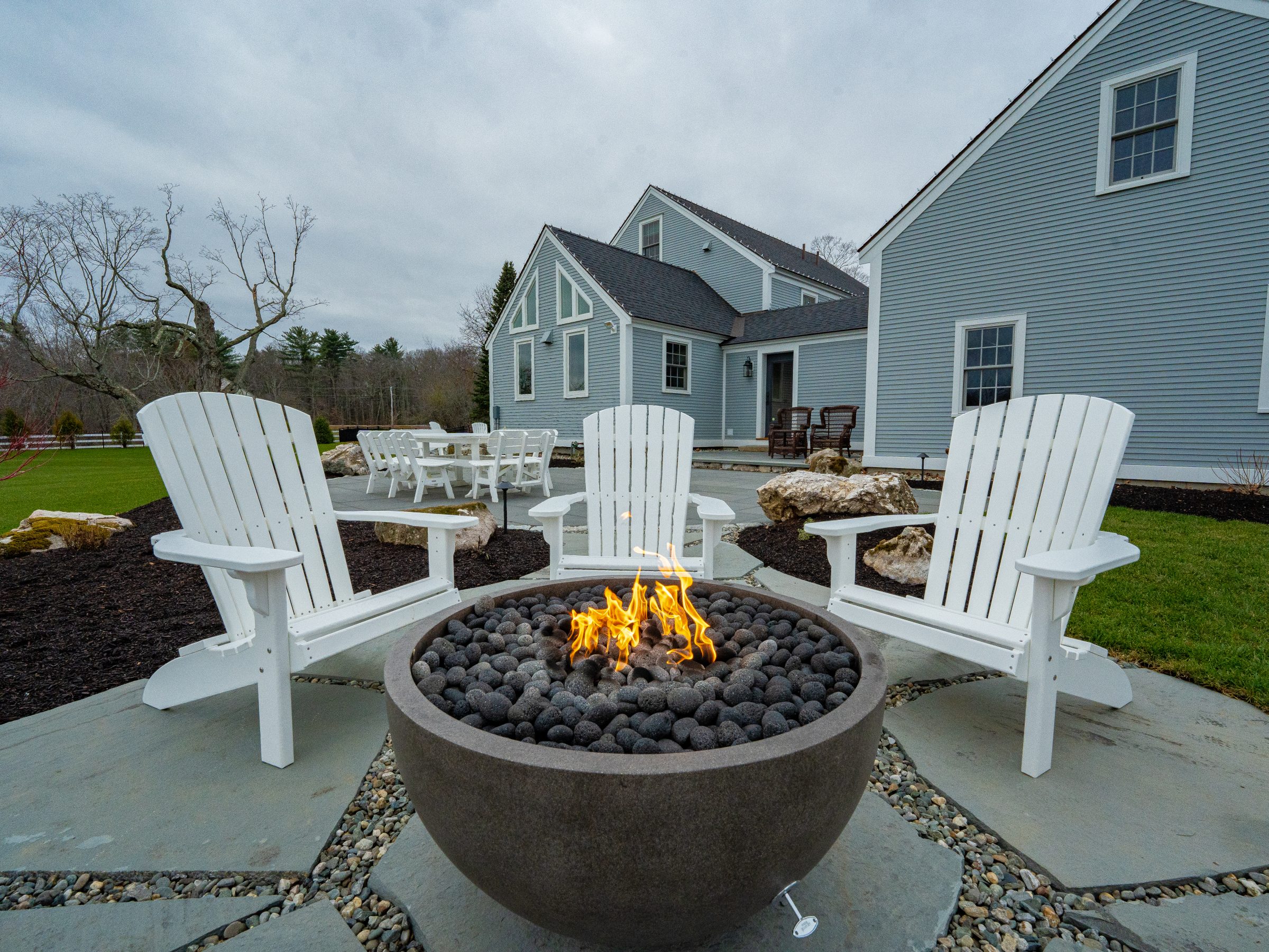 Backyard fire pit with white Adirondack chairs