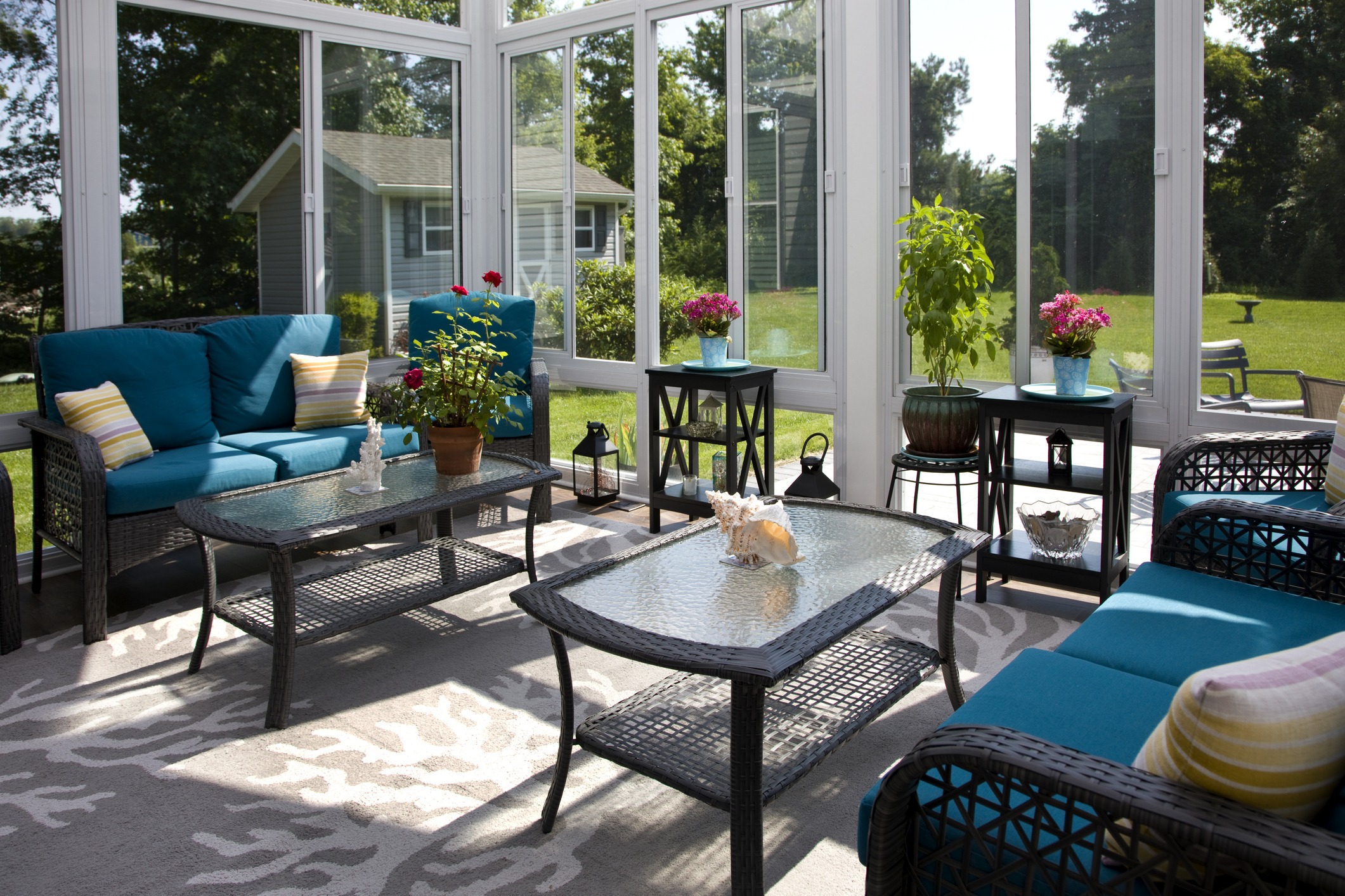Bright sunroom with wicker furniture and teal cushions